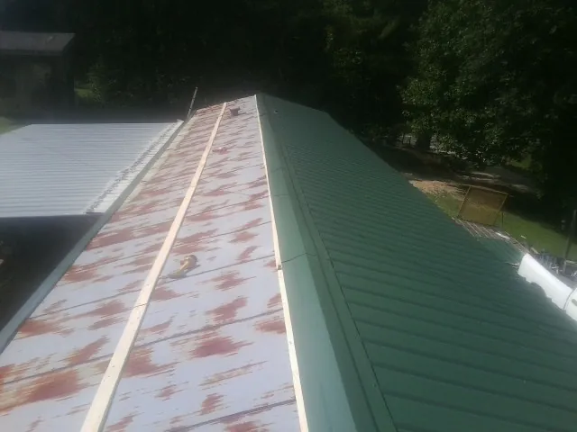 Old rusted panels beside newly installed green metal roofing — Wind Damage Roof Repair by Roofing Brothers in Belden