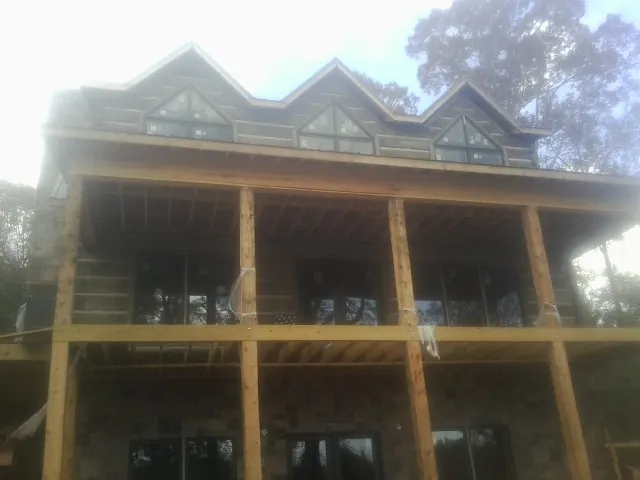 Dormers and porch framing on a large log home under construction — Roof Coating work by our crew in Belden